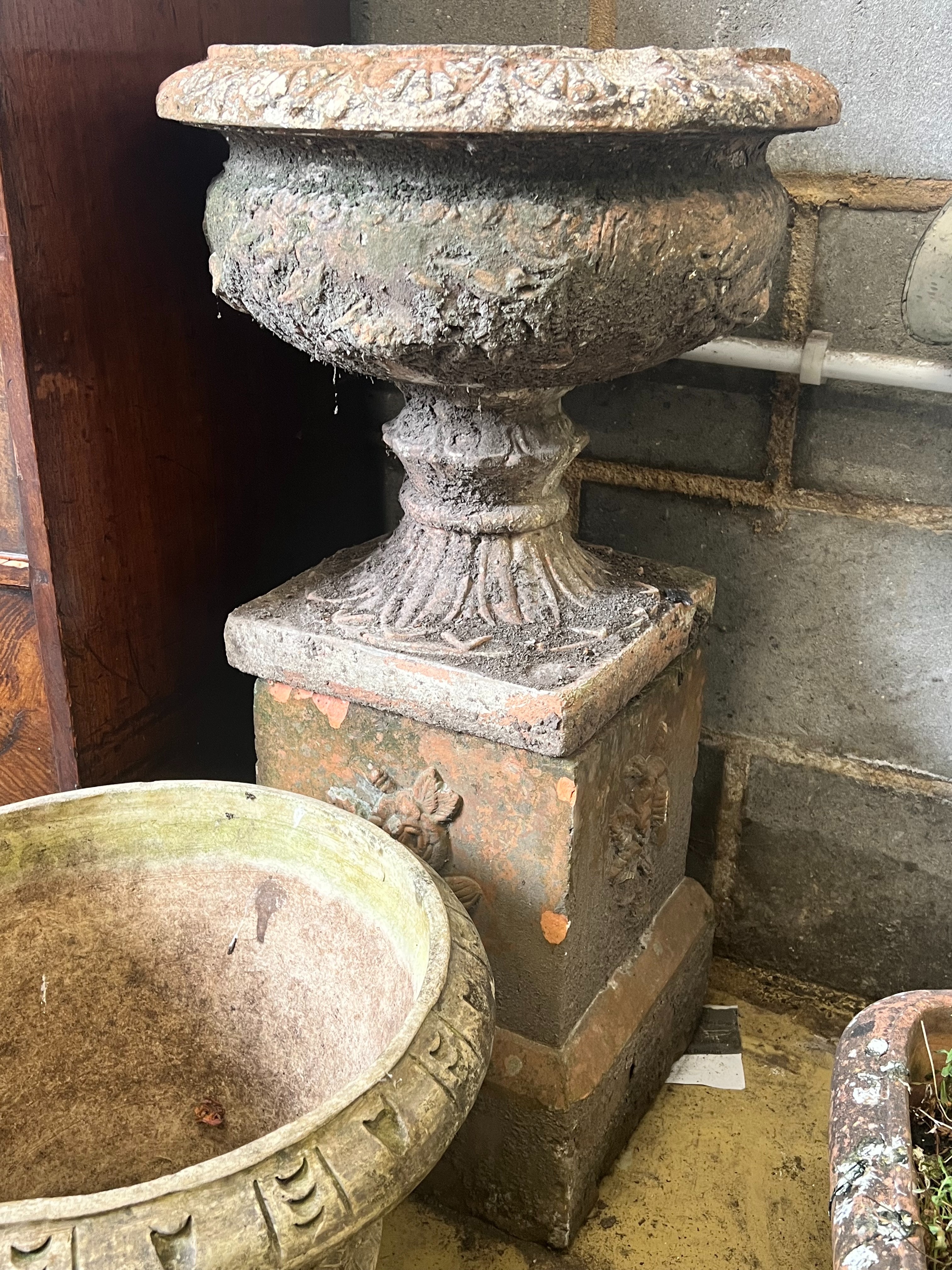 A terracotta campana garden urn on square plinth, height 77cm., together with a circular reconstituted stone garden planter